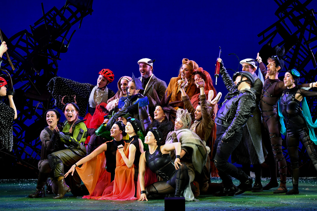 Group of students, dressed in costumes, singing together on stage.